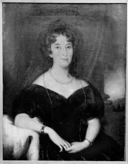 Curly-haired woman with clasped hands in a v-neck dress
