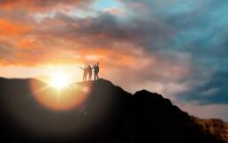 Colour photo of three people standing on top of a hill