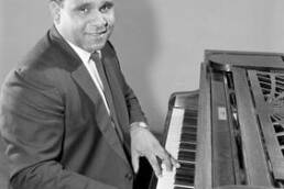 Harold Blair in a suit playing the piano