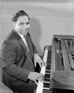 Harold Blair in a suit playing the piano