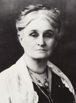 Woman with grey hair in a bun wearing three necklaces