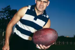 Muscular man in a striped sleeveless shirt holding a football