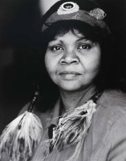 Headshot of a woman with long hair wearing a headband and feathers