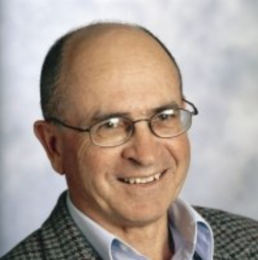 Headshot of a balding older man wearing classes, a white collared shirt and plaid jacket