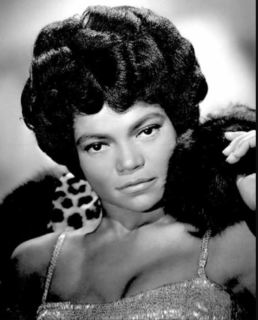 Black and white headshot of a woman wearing a sequin dress, fur on her shoulders and hair in a beehive style