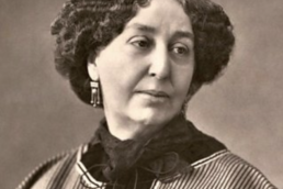 Black and white headshot of a sombre woman wearing a striped blouse, lacy scarf and earrings