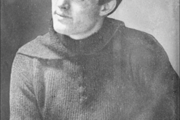Black and white photo of a dark-haired young man who is seated and looking away from the camera