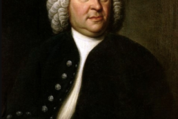 Portrait of a heavyset man wearing a white curly wig and black jacket holding a musical score.
