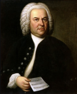 Portrait of a heavyset man wearing a white curly wig and black jacket holding a musical score.