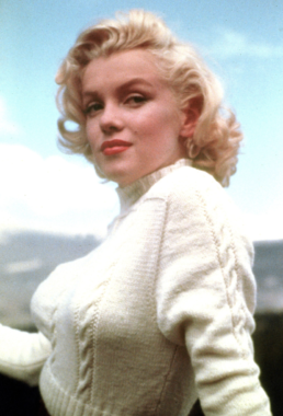 Headshot of a blonde woman wearing a white sweater and red lipstick
