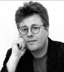 Black and white headshot of a middle-aged man with glasses resting his hand on the side of his face