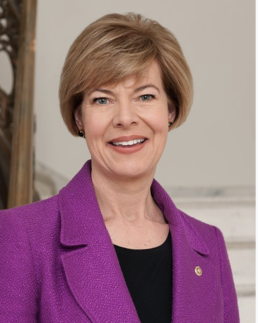 Headshot of a smiling woman with a brown bob wearing a magenta suit jacket and black blouse